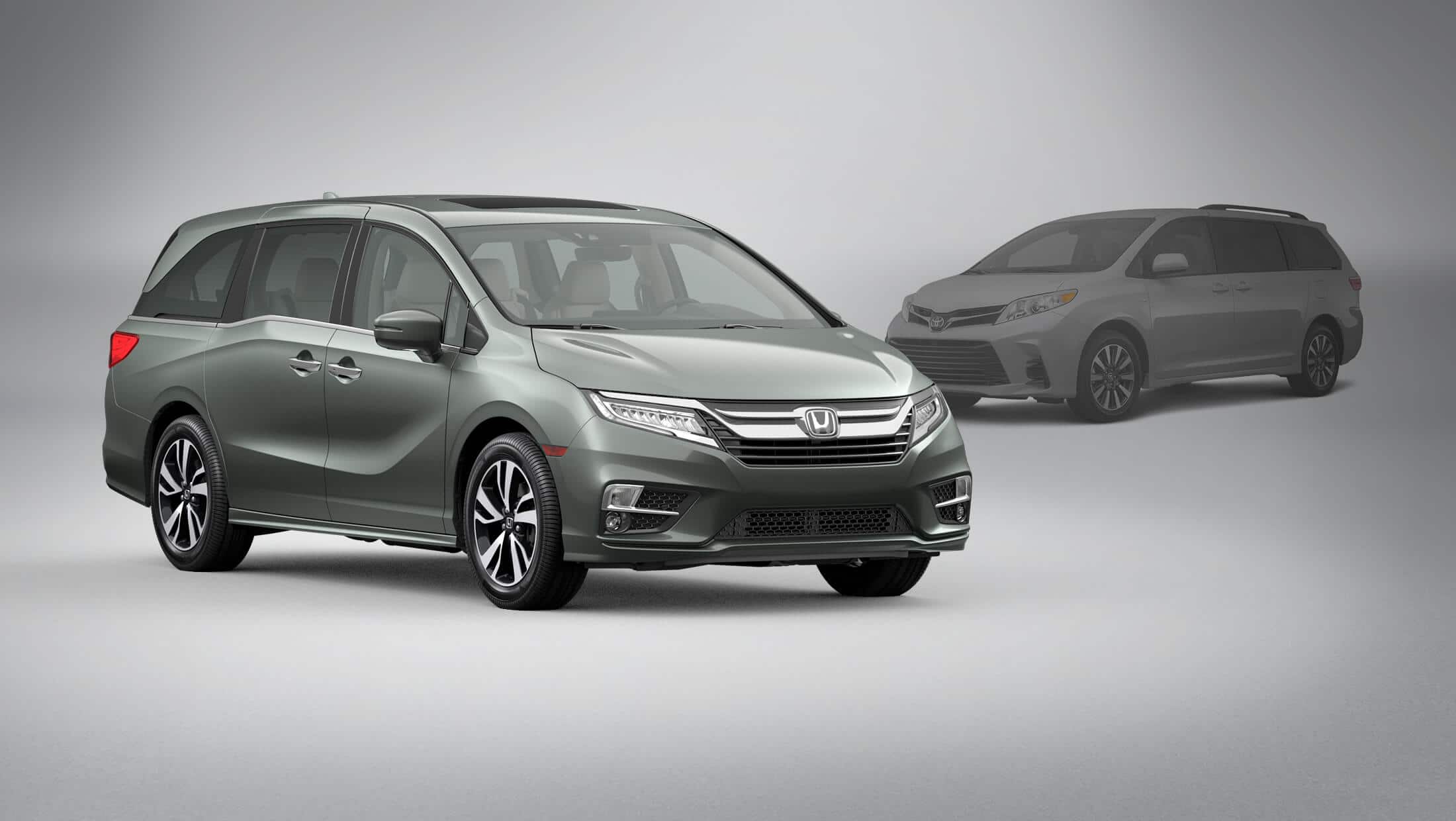 Front 3/4 passenger-side view of 2020 Honda Odyssey in Forest Mist Metallic parked in front of 2020 Toyota Sienna.